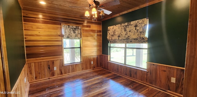 spare room with wooden walls, wood-type flooring, and plenty of natural light