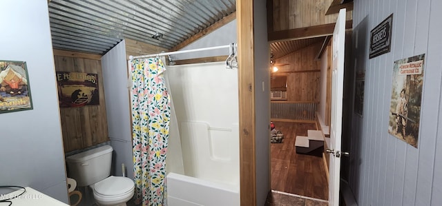 bathroom featuring lofted ceiling, hardwood / wood-style floors, toilet, shower / bath combo with shower curtain, and wood walls