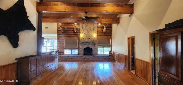 unfurnished living room featuring hardwood / wood-style flooring, wooden walls, and plenty of natural light