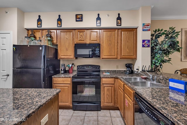 kitchen with dark stone countertops, sink, black appliances, light tile patterned flooring, and crown molding