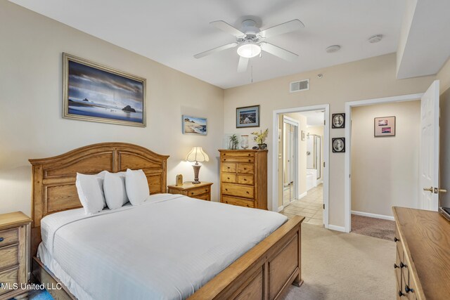 bedroom featuring light carpet, ensuite bath, and ceiling fan