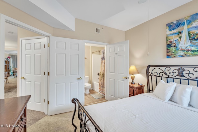 bedroom featuring light carpet, ensuite bath, and visible vents