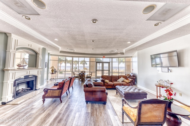 living room featuring a textured ceiling, a wealth of natural light, light wood-type flooring, and a raised ceiling