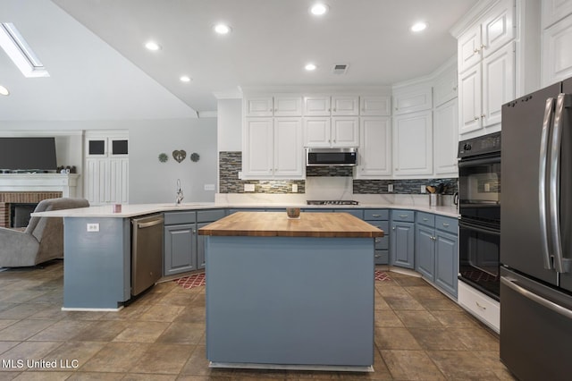 410 Woodland Hills Ct, Madison, MS 39110 - kitchen with wooden counters, appliances with stainless steel finishes, a peninsula, white cabinets, and tasteful backsplash