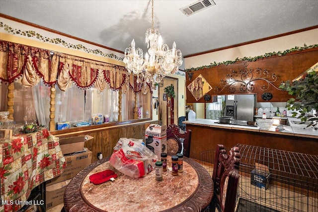 dining area with crown molding, a chandelier, and a textured ceiling