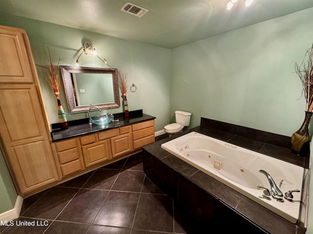 bathroom featuring vanity, a relaxing tiled tub, tile patterned floors, and toilet