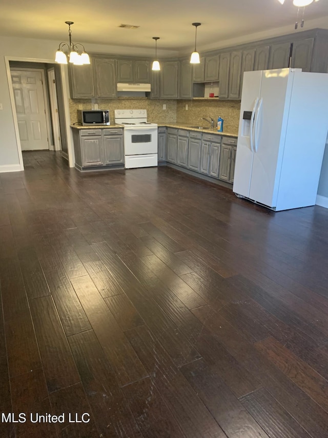 kitchen with sink, hanging light fixtures, dark hardwood / wood-style floors, white appliances, and backsplash