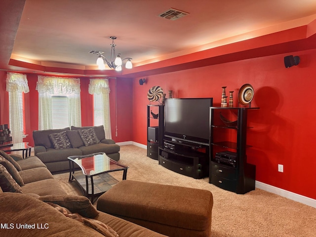 living room with carpet, an inviting chandelier, and a tray ceiling