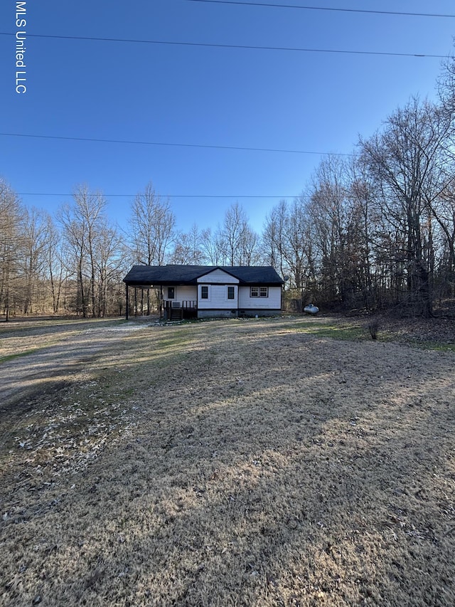 view of front of property featuring dirt driveway and a carport