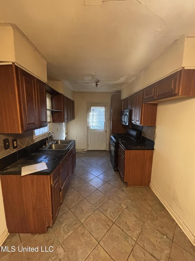 kitchen featuring decorative backsplash, dark countertops, black gas stove, open shelves, and a sink