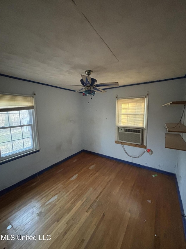 empty room with ceiling fan, wood finished floors, cooling unit, and baseboards