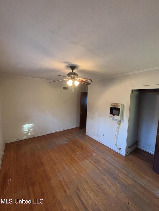 interior space featuring a ceiling fan, visible vents, heating unit, and hardwood / wood-style flooring