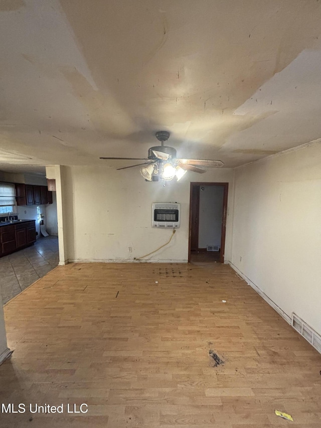 interior space with heating unit, visible vents, a ceiling fan, a sink, and light wood-type flooring