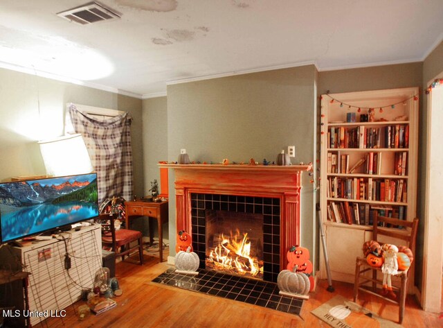 living room featuring a fireplace, ornamental molding, and hardwood / wood-style flooring