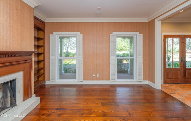 unfurnished living room featuring built in features, crown molding, a high end fireplace, wood finished floors, and baseboards