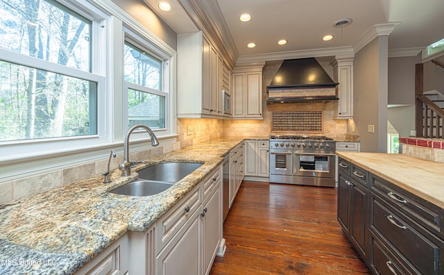 kitchen featuring custom range hood, wood counters, stainless steel appliances, crown molding, and a sink