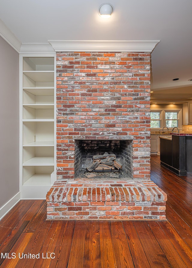 room details with ornamental molding, a fireplace, and wood finished floors