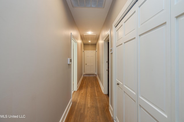 corridor with attic access, visible vents, baseboards, and dark wood finished floors