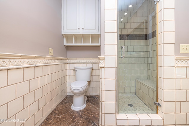 full bath featuring toilet, a shower stall, tile walls, and wainscoting