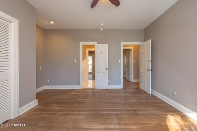 unfurnished bedroom with ceiling fan, baseboards, and wood finished floors