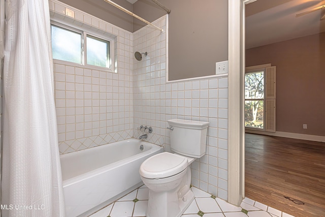 bathroom with shower / tub combo with curtain, plenty of natural light, tile walls, and toilet