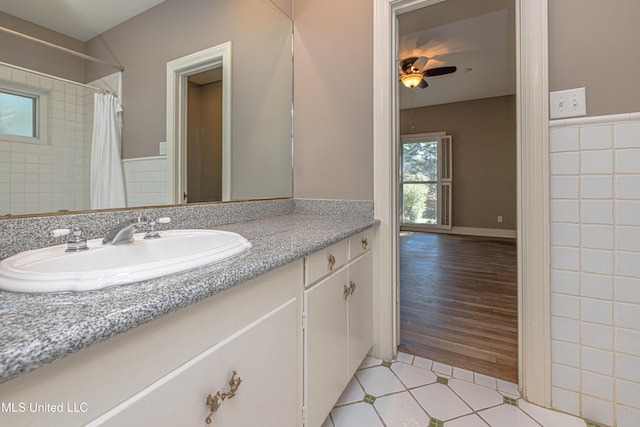 full bathroom with ceiling fan, a shower with shower curtain, vanity, and tile walls