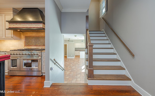 stairway featuring crown molding, baseboards, and wood finished floors