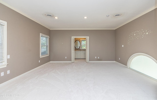 empty room with crown molding, light colored carpet, visible vents, and plenty of natural light