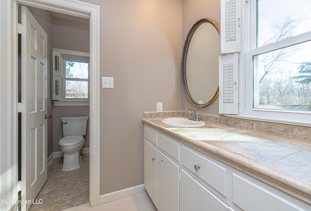 bathroom with toilet, vanity, and baseboards