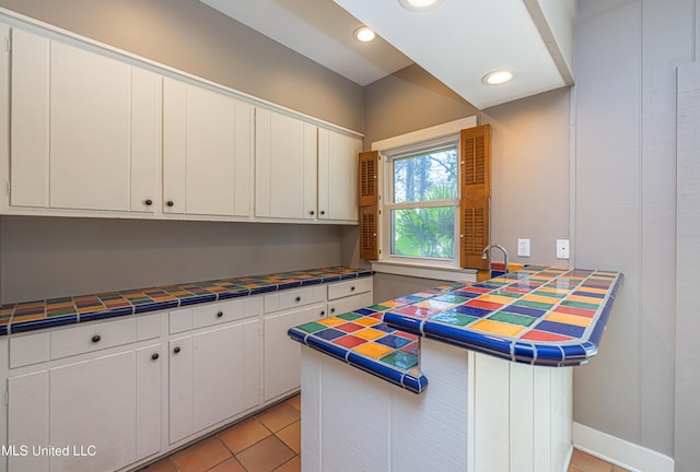 kitchen featuring light tile patterned floors, tile counters, white cabinets, a peninsula, and recessed lighting