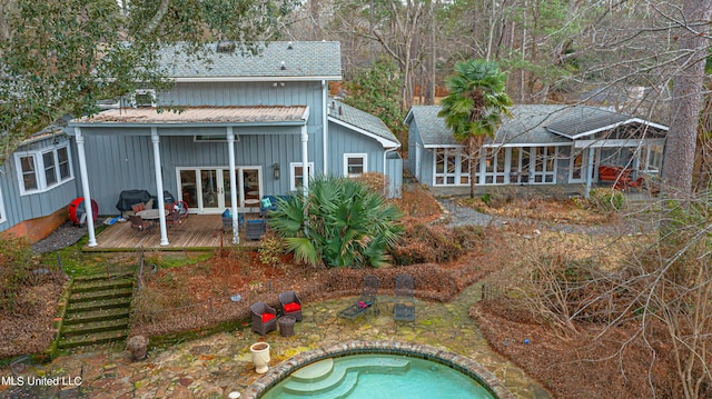 back of property with french doors, a shingled roof, a wooden deck, and a jacuzzi