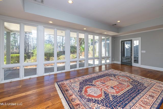 interior space with baseboards, plenty of natural light, visible vents, and wood finished floors