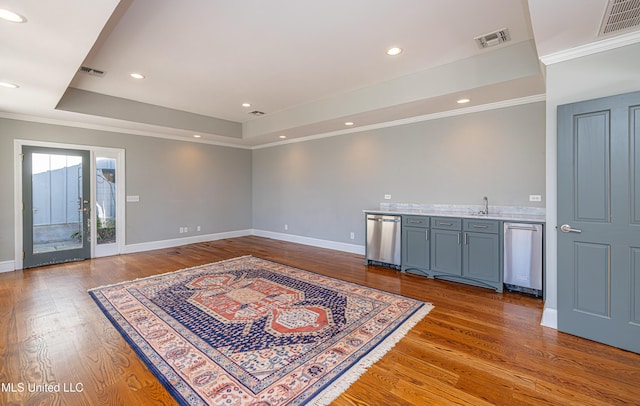 interior space with wet bar, a raised ceiling, and visible vents