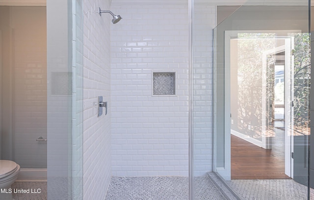 bathroom featuring speckled floor, a shower stall, toilet, and baseboards