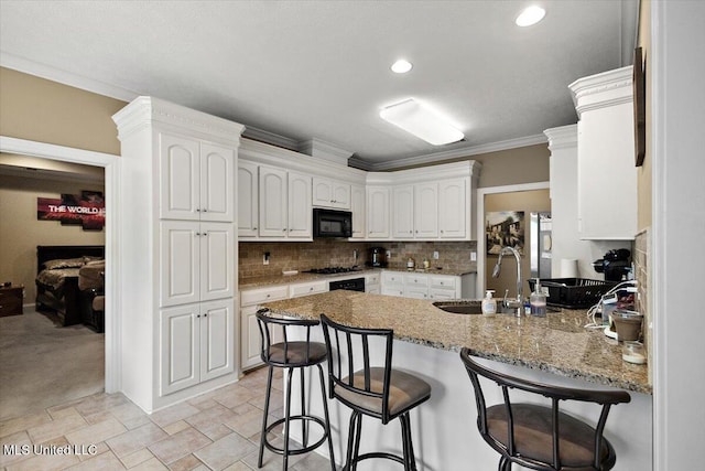 108 Merlot Cv, Clinton, MS 39056 - kitchen featuring a sink, a peninsula, black microwave, a kitchen breakfast bar, and white cabinetry