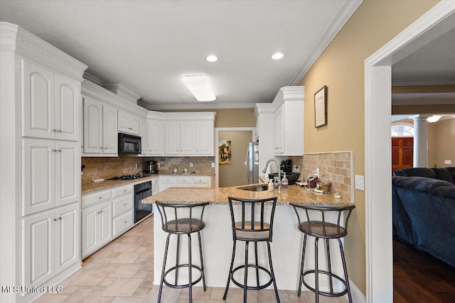 108 Merlot Cv, Clinton, MS 39056 - kitchen featuring black appliances, a peninsula, white cabinetry, light stone countertops, and ornamental molding