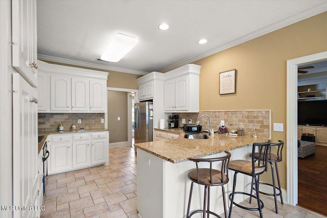 108 Merlot Cv, Clinton, MS 39056 - kitchen featuring stainless steel refrigerator with ice dispenser, a sink, a peninsula, decorative backsplash, and a kitchen bar