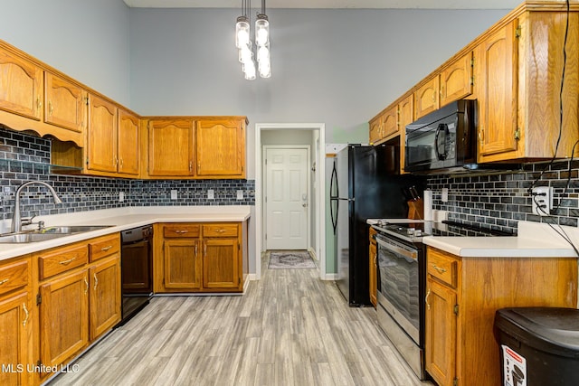 9821 Morgan Manor Dr, Olive Branch, MS 38654 - kitchen with black appliances, brown cabinetry, light wood-style floors, and a towering ceiling