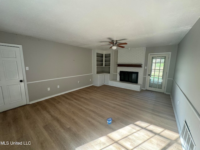 unfurnished living room featuring a textured ceiling, a fireplace, light hardwood / wood-style floors, and ceiling fan