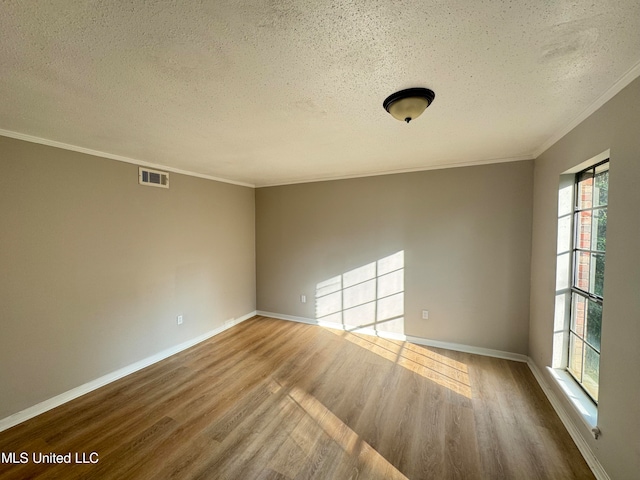 spare room with a textured ceiling, ornamental molding, and hardwood / wood-style floors