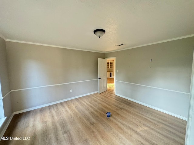 empty room featuring ornamental molding and light hardwood / wood-style floors