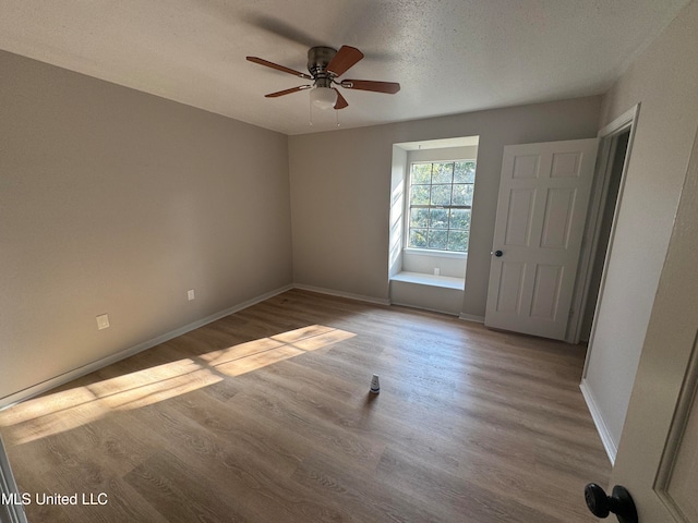 empty room with ceiling fan, a textured ceiling, and light wood-type flooring