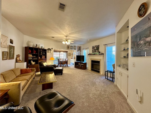 living room with ceiling fan, a textured ceiling, and light colored carpet