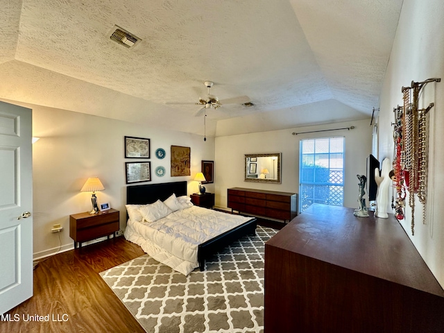 bedroom with a textured ceiling, vaulted ceiling, dark hardwood / wood-style floors, and ceiling fan