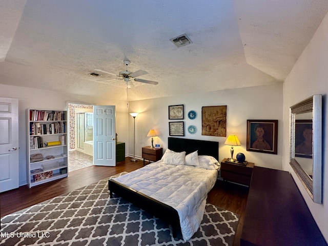 bedroom with dark wood-type flooring, vaulted ceiling, a textured ceiling, and ceiling fan