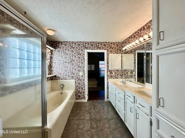 bathroom with vanity, a tub to relax in, a textured ceiling, and tile patterned flooring