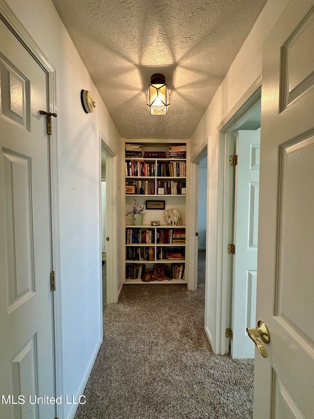 corridor featuring a textured ceiling and carpet flooring