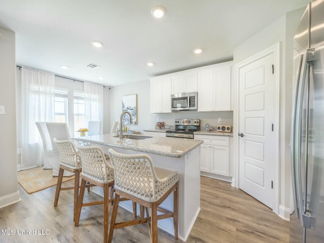 9626 W Oaklawn Rd, Biloxi, MS 39532 - kitchen featuring appliances with stainless steel finishes, a kitchen island with sink, a breakfast bar, light wood-type flooring, and recessed lighting