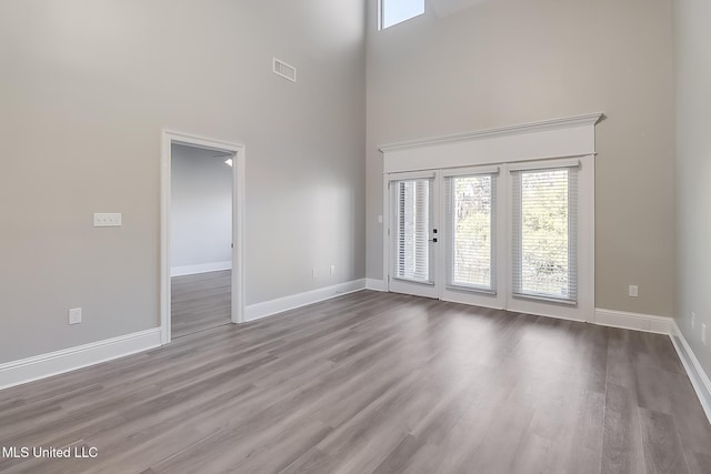 unfurnished room featuring a healthy amount of sunlight, french doors, wood-type flooring, and a high ceiling