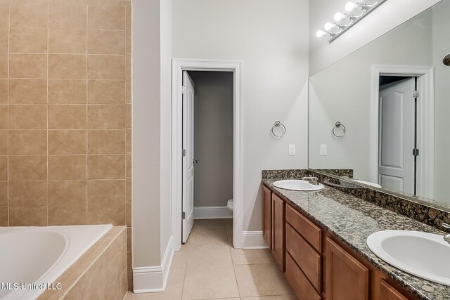 bathroom featuring vanity, tile patterned flooring, toilet, and tiled tub